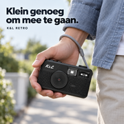 Zwarte K&L Retro Camera met grijze polsband in de hand, onderweg aan zee.