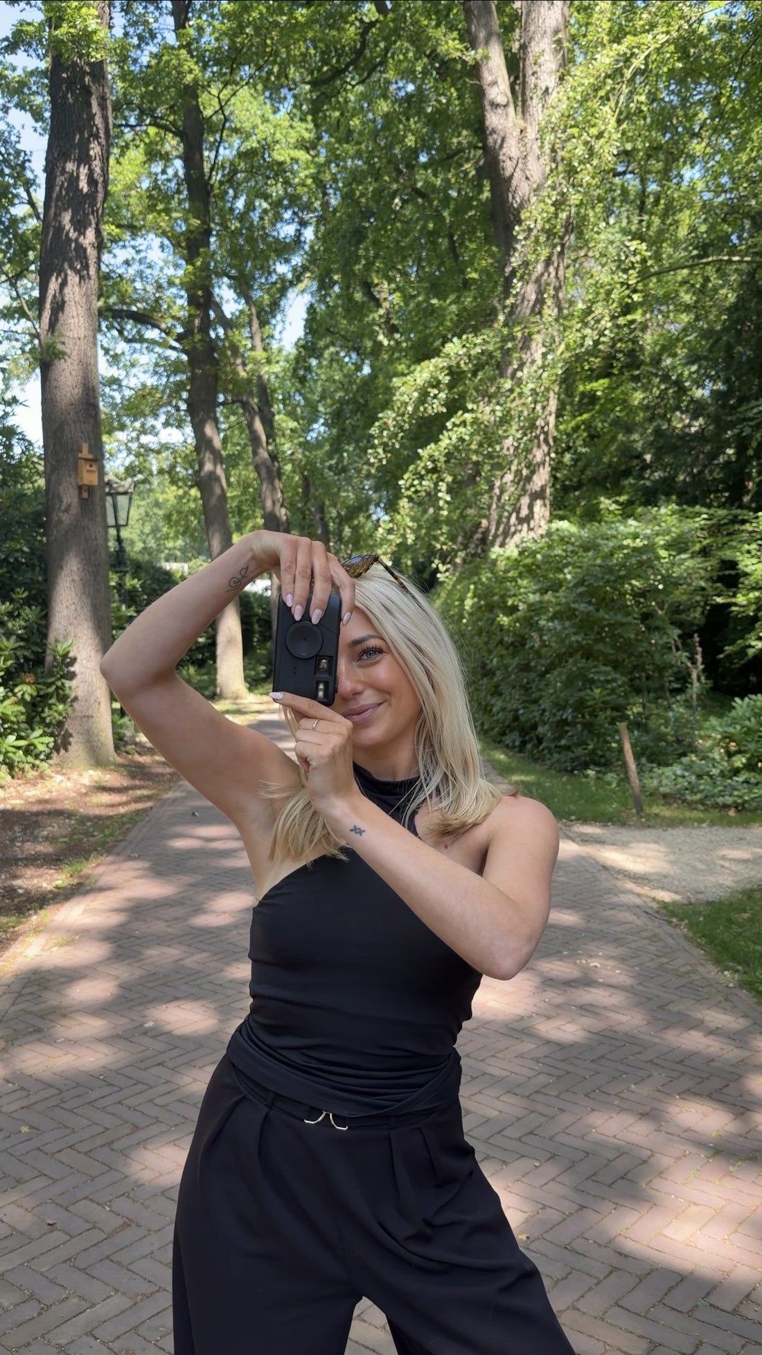 Vrouw met de zwarte K&L Retro Camera tijdens een wandeling tussen de bomen